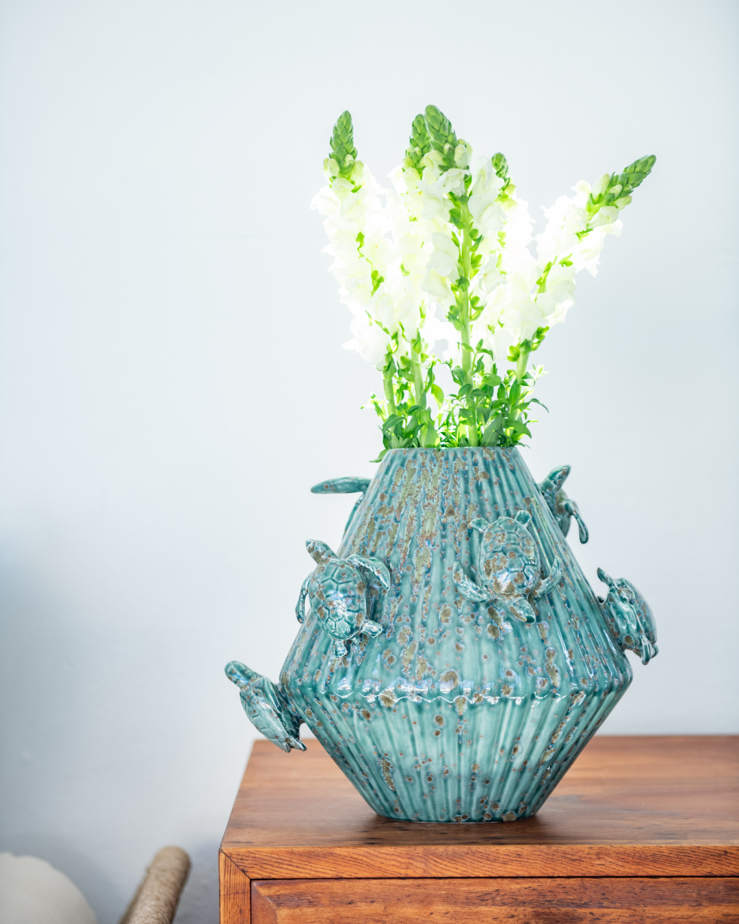 Green & Matt White decorative vase with 3d sea turtles attached on a matching pedestal with a person holding a white version in the background