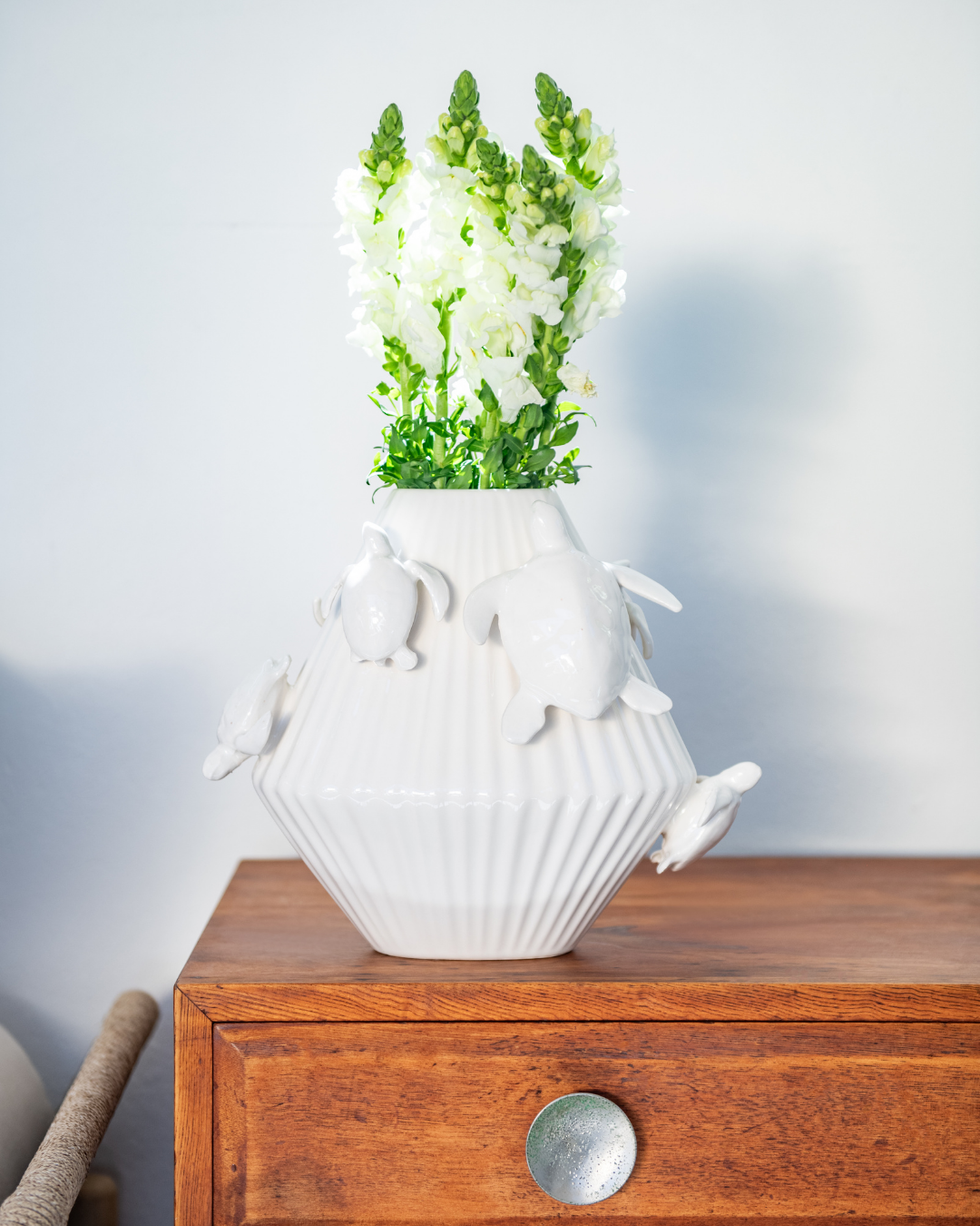 Green & Matt White decorative vase with 3d sea turtles attached on a matching pedestal with a person holding a white version in the background