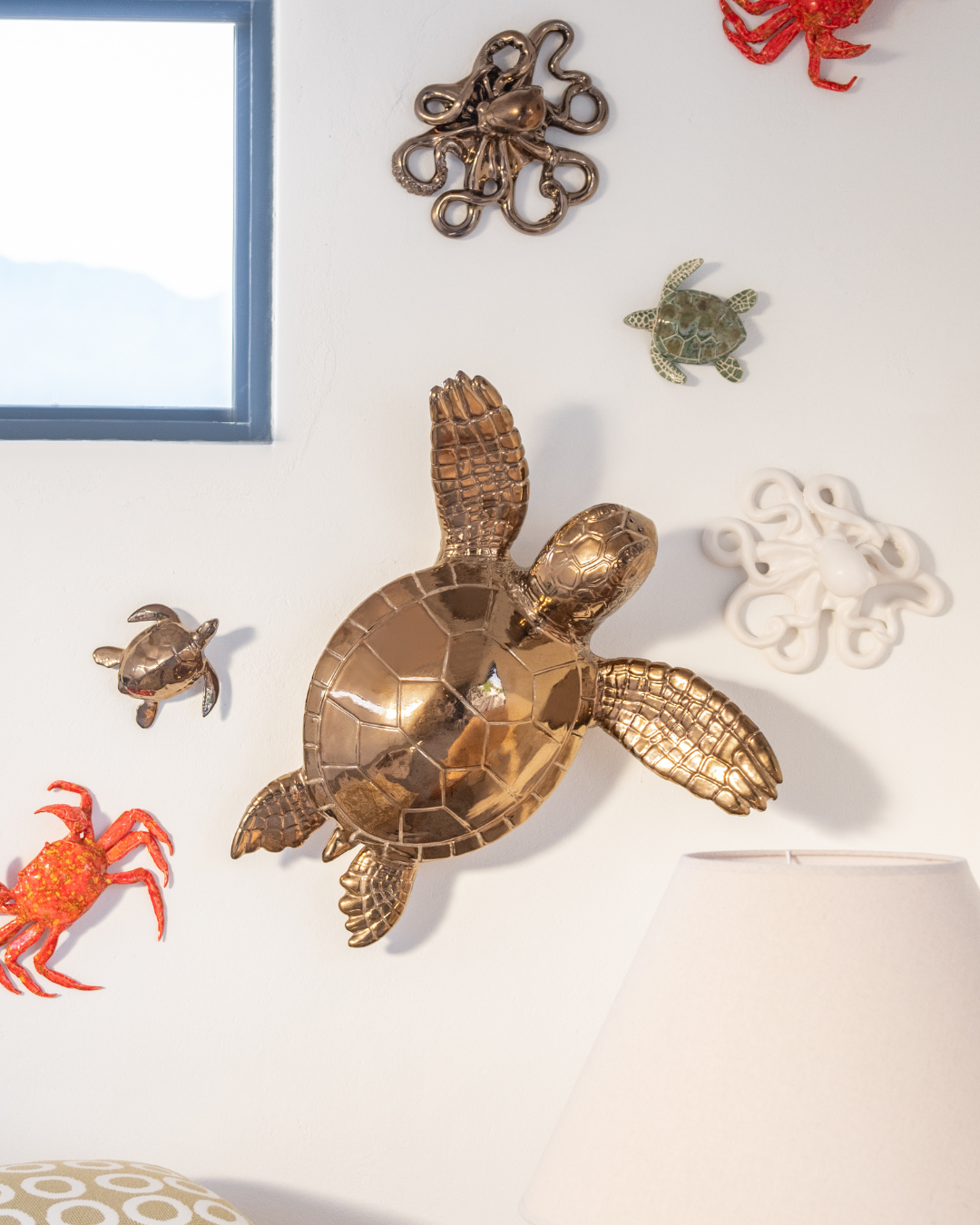 Decorative bronze sea turtle wall art on a white wall with other sea-themed decorations.