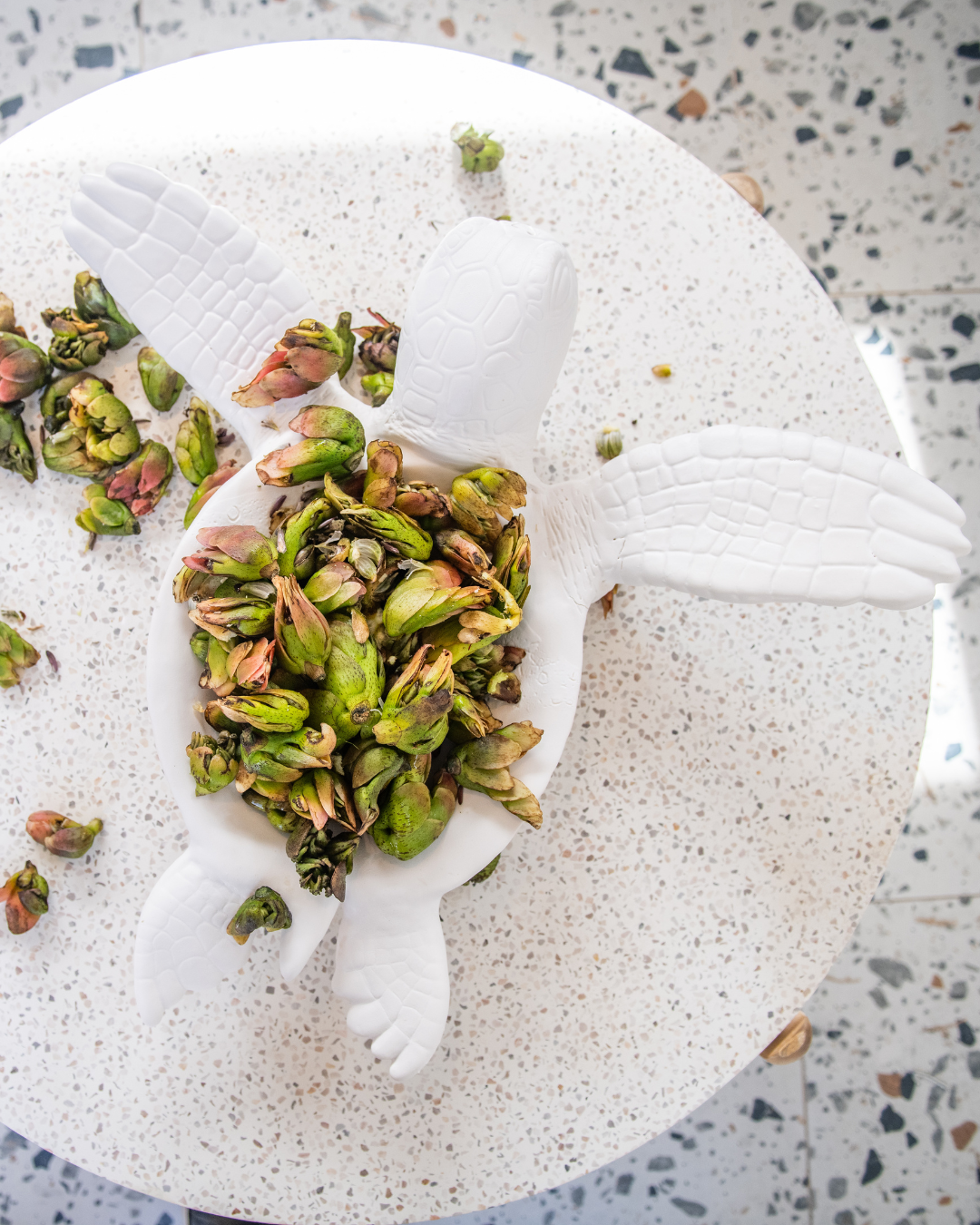 Large White ceramic turtle designed as a fruit bowl with green leaves on a speckled gray surface