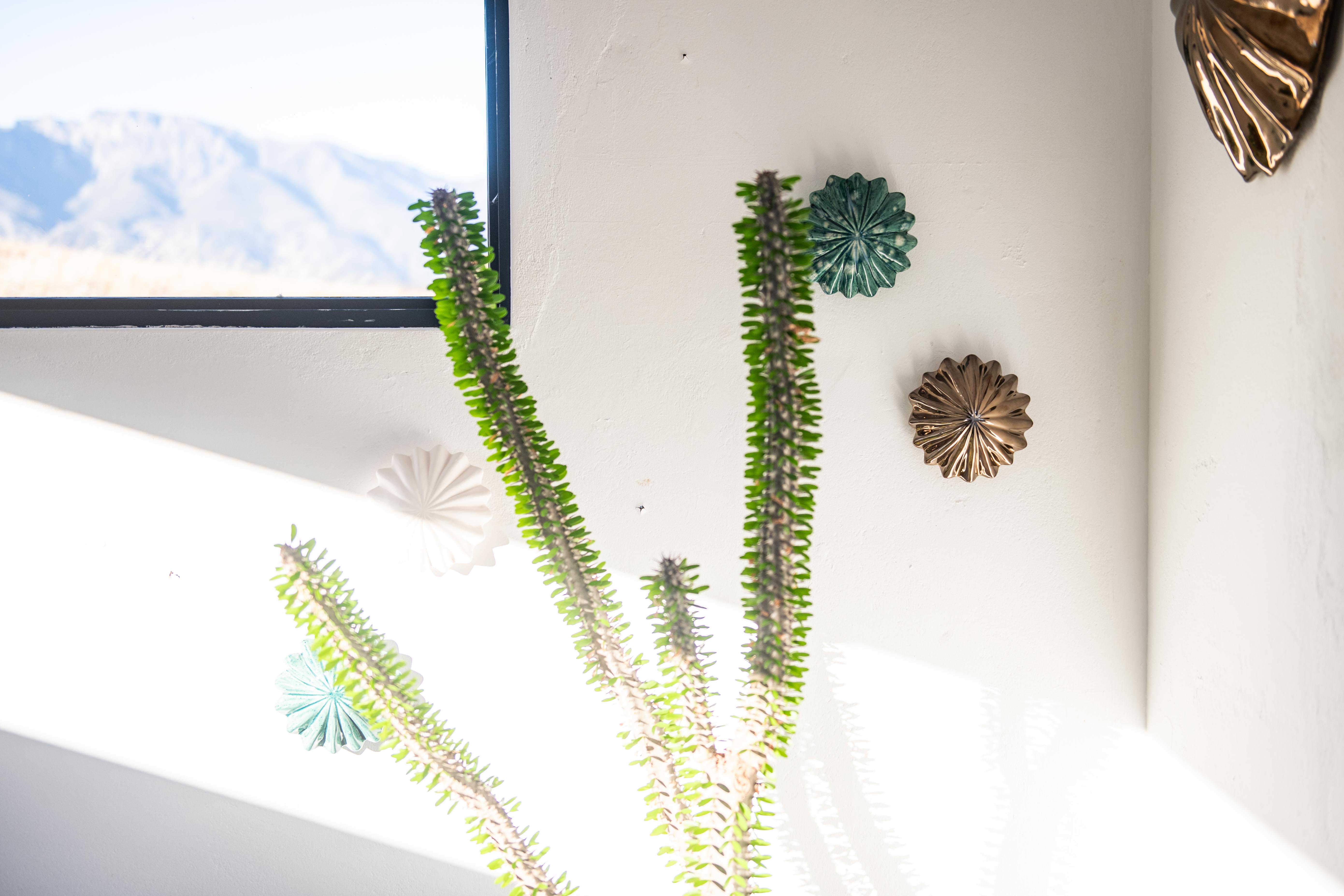Decorative wall art with green and gold elements on a white wall.
