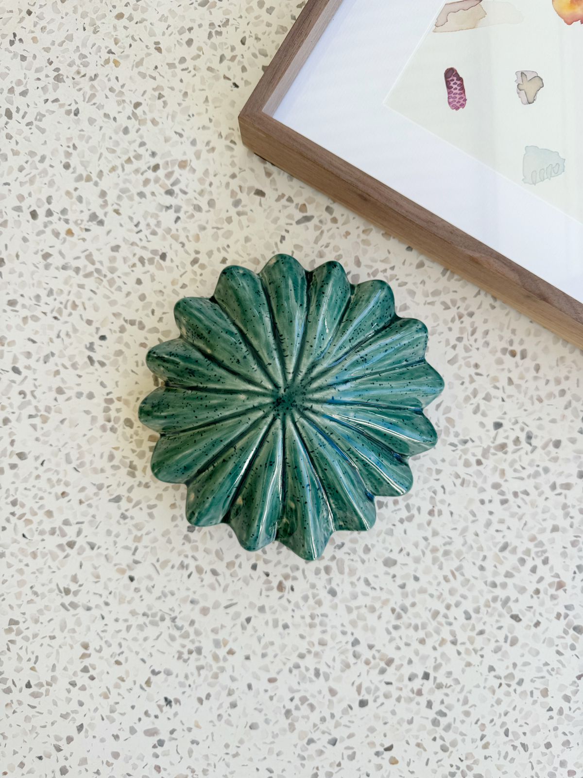 Green ceramic object on a textured surface with a blurred background