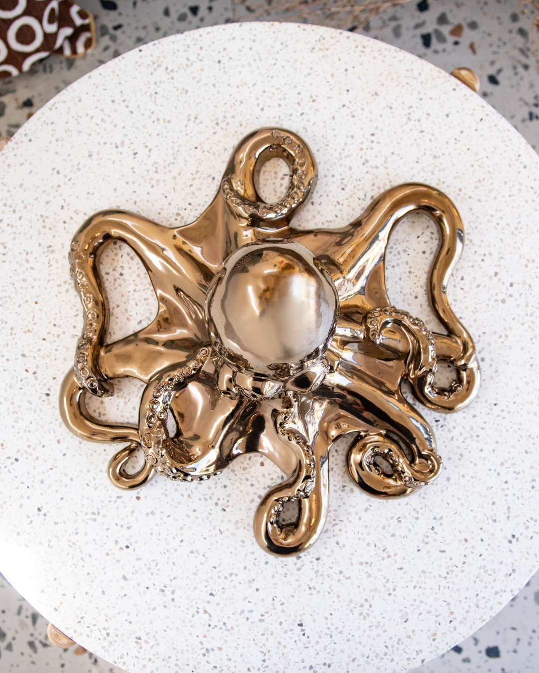 Decorative gold octopus sculpture on a textured white surface