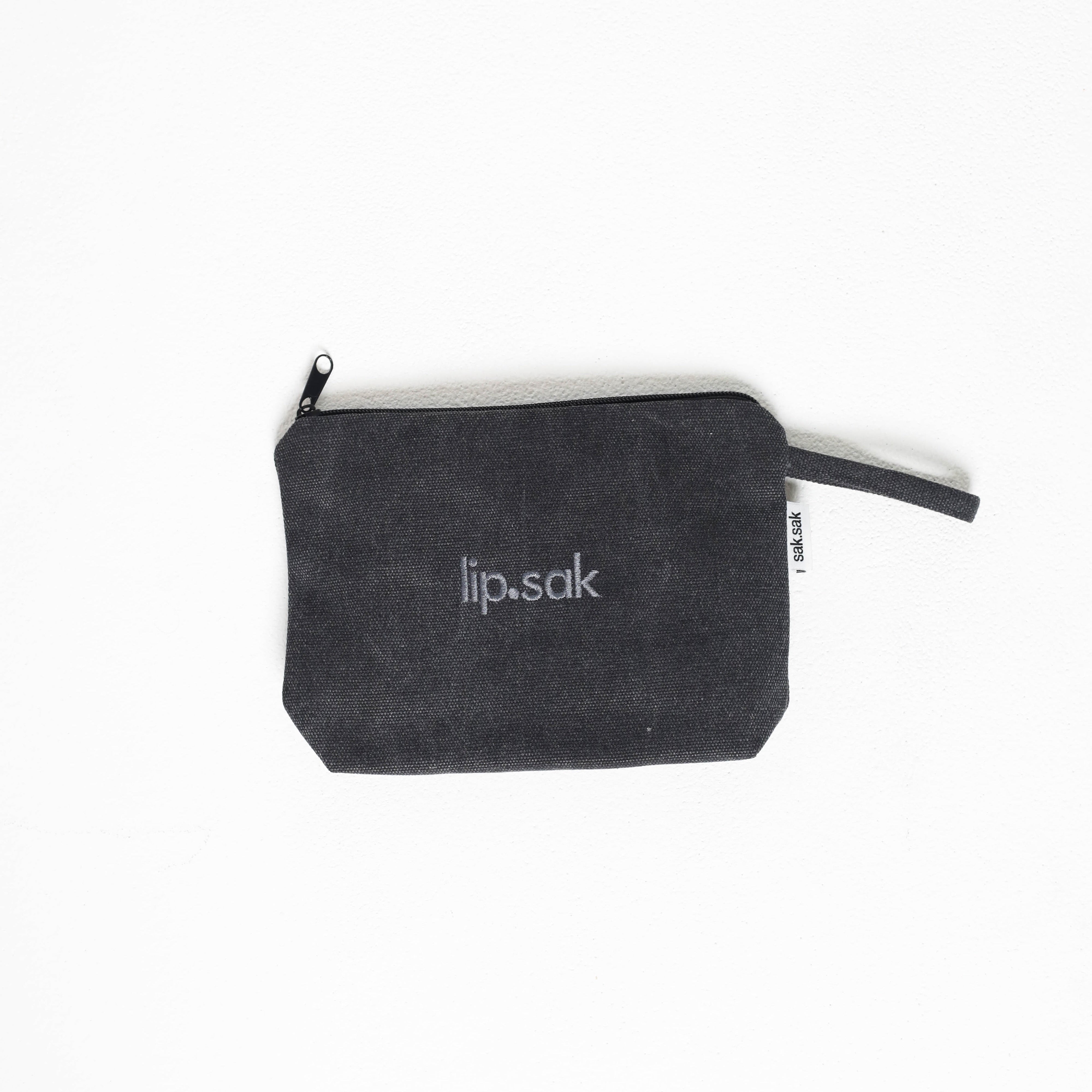 Black zippered pouch with 'lip.sak' branding on a white background