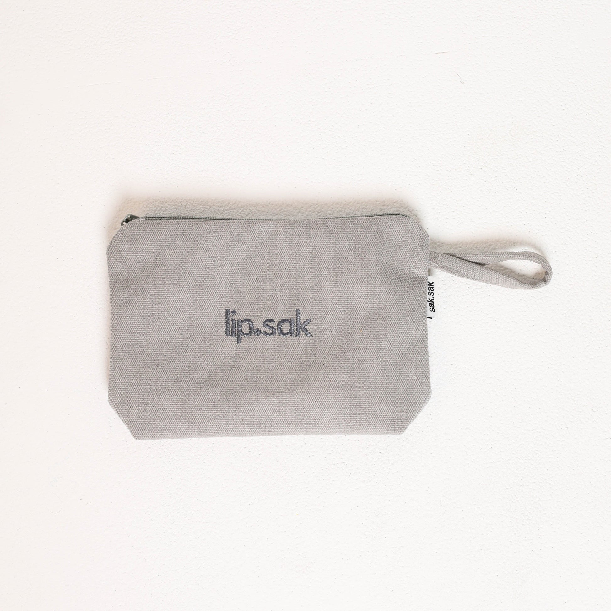 Gray pouch with 'lip.sak' branding on a white background