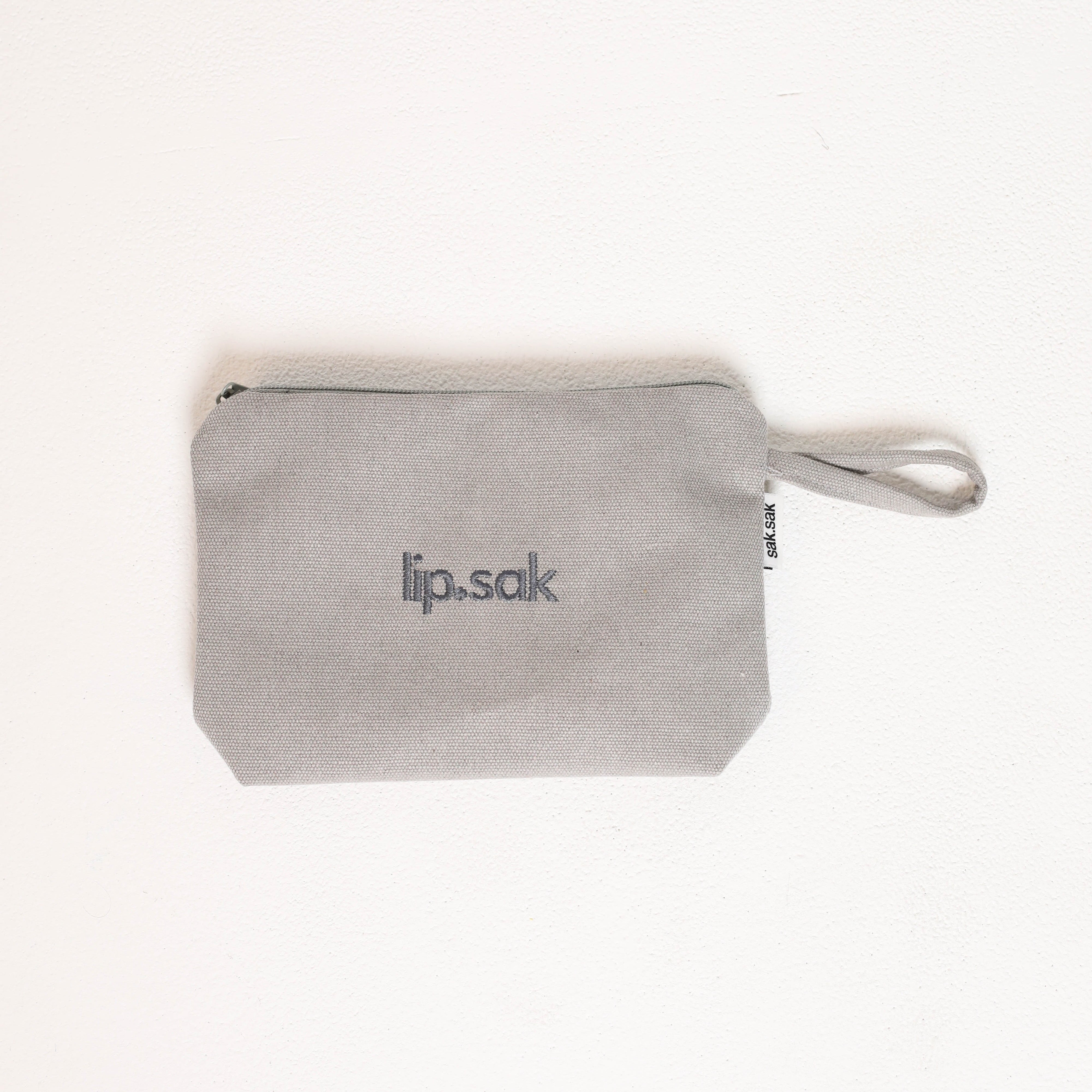 Gray pouch with 'lip.sak' branding on a white background