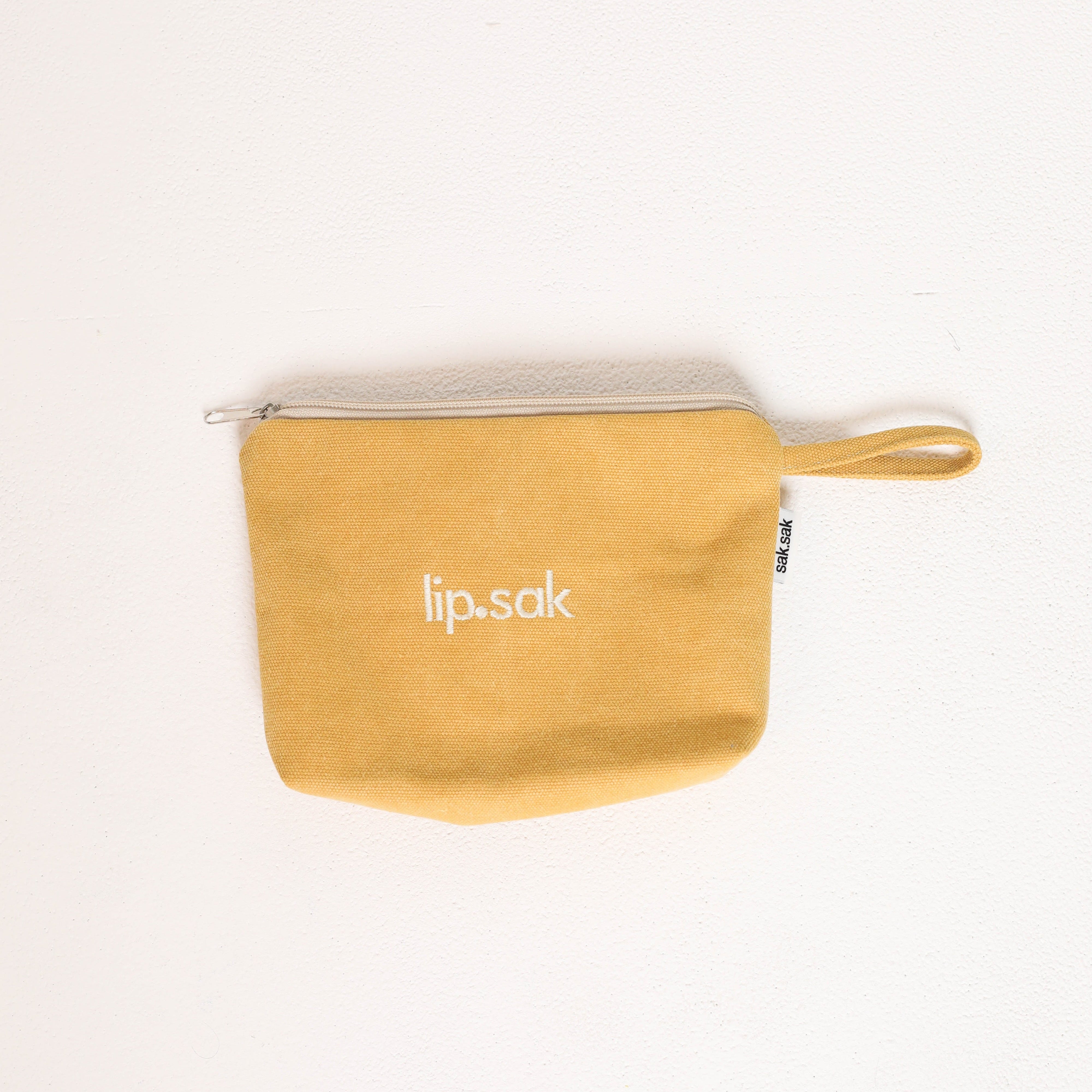 Yellow pouch with 'lip.sak' branding on a white background