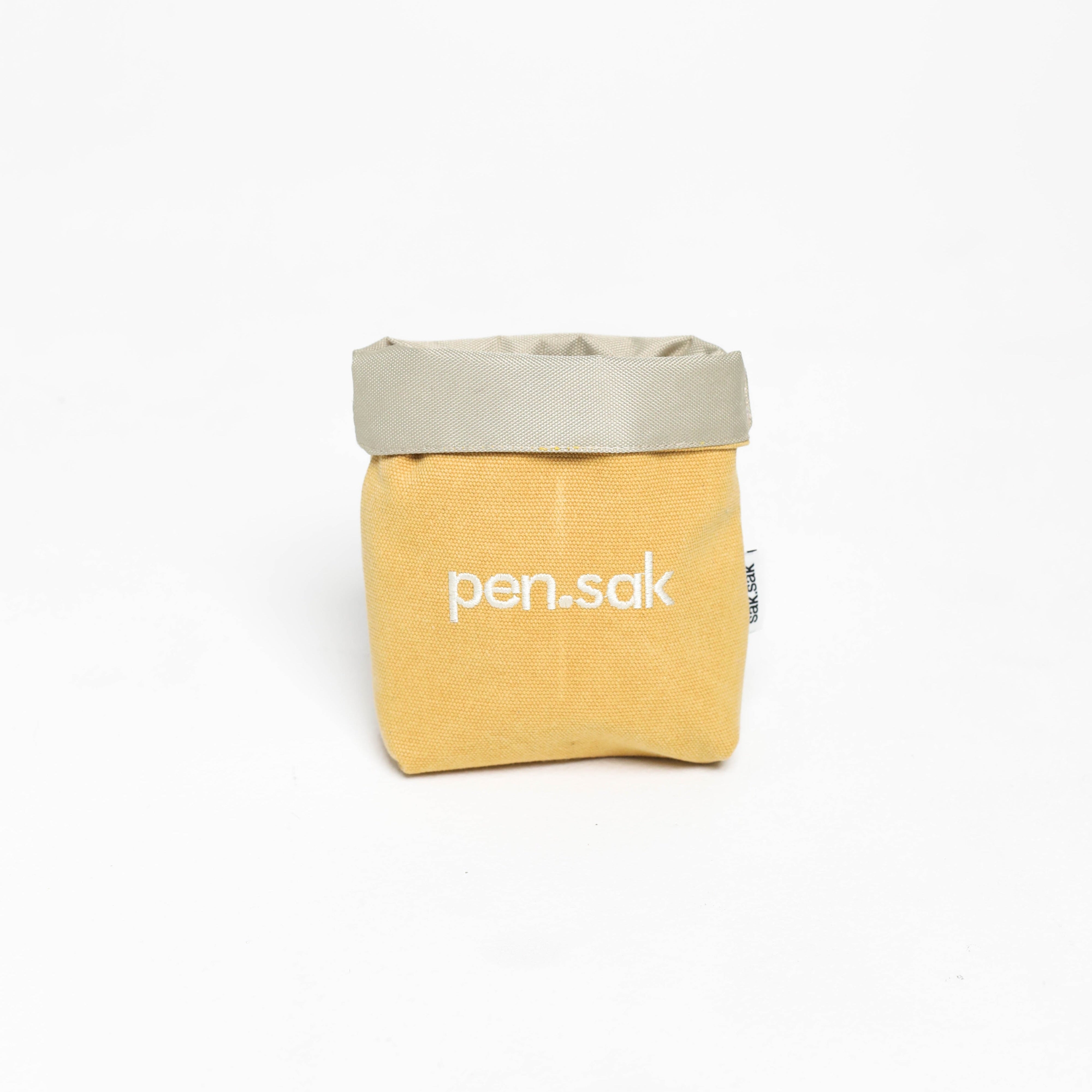 Yellow pouch with a gray top and 'pen.sak' branding on a white background